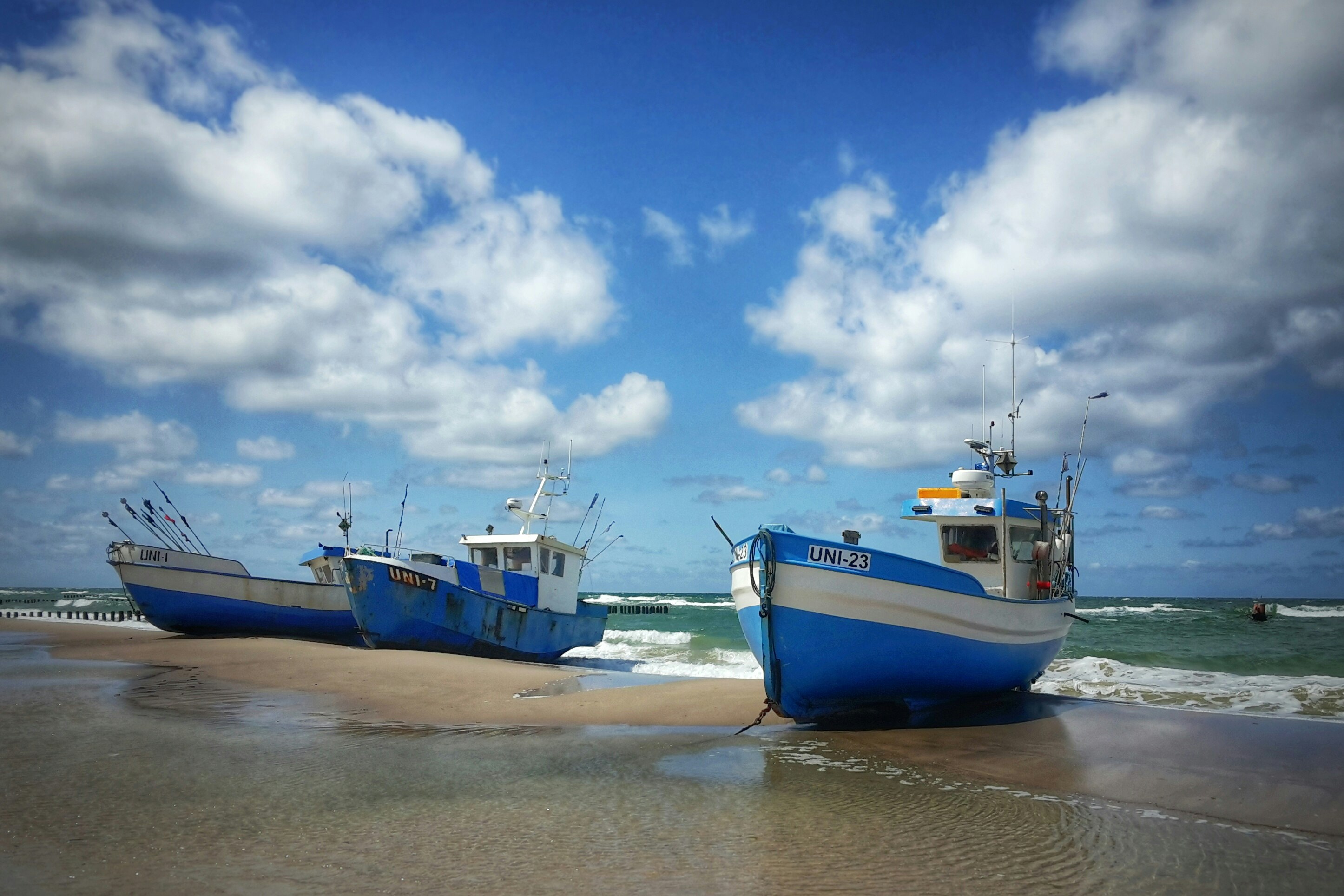 three blue boat docked on seashore during daytime